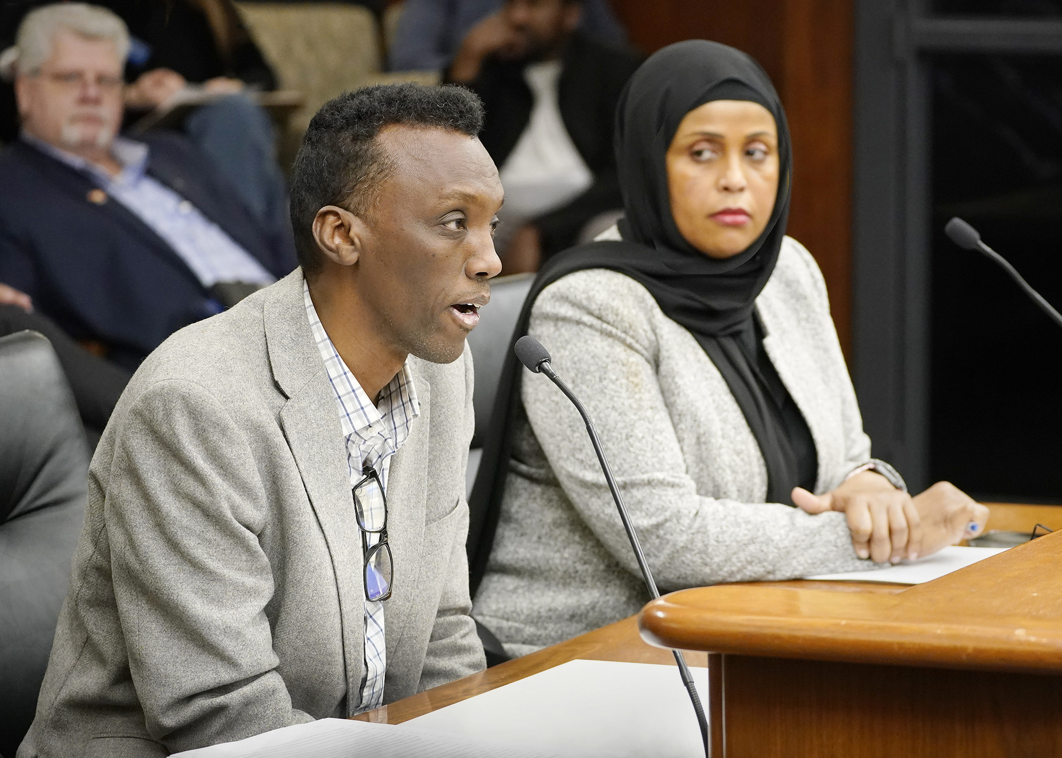 Eid Ali, president of the Minnesota Uber/Lyft Drivers Association, testifies before the House commerce committee in support of a bill sponsored by Rep. Hodan Hassan, right, that would regulate transportation network companies. (Photo by Andrew VonBank)